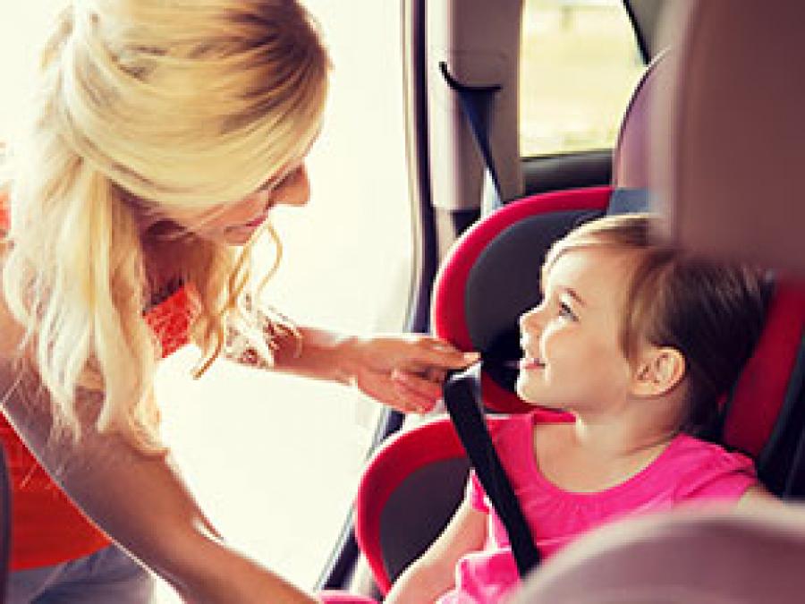 A mom putting her daughter into a carseat