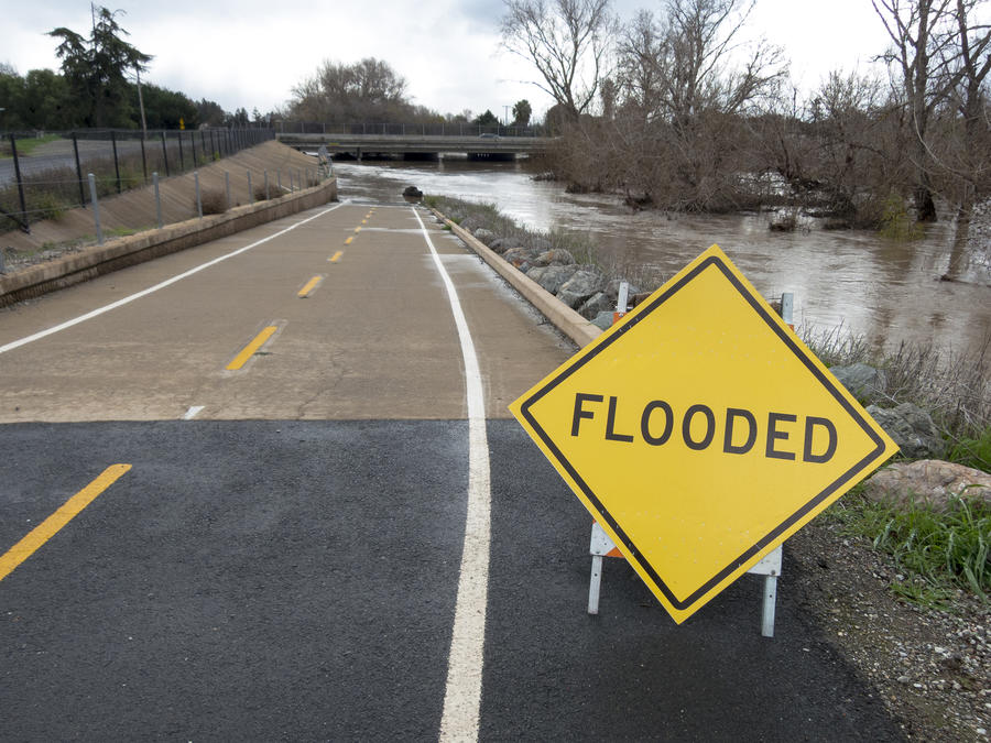 黃色“洪水”警告牌放置在洪水氾濫的河流前