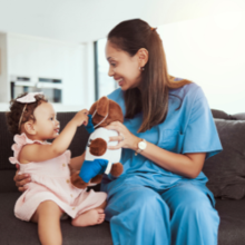 nurse playing with child and teddy bear.